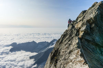 man climbing on gray mountain man climbing on gray mountain