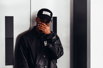 man covering his face in front of gray door