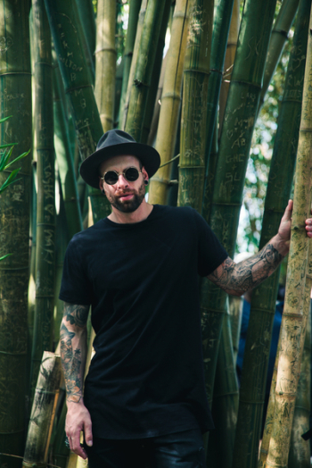 Man Holding Bamboo Plant Wearing Sunglasses and Fedora Hat