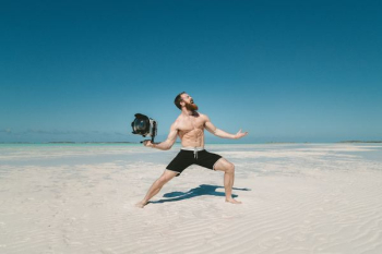 man holding camera on seashore