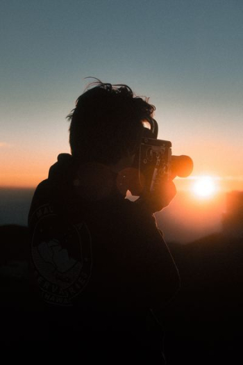 man holding classic camera during golden hour man holding classic camera during golden hour