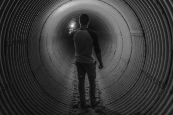 man holding light walking inside tunnel man holding light walking inside tunnel