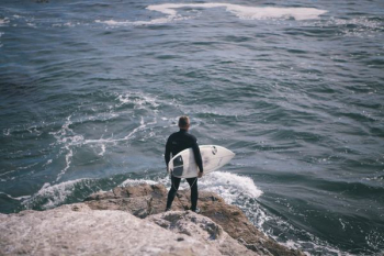 man holding surfboard standing in front of sea man holding surfboard standing in front of sea