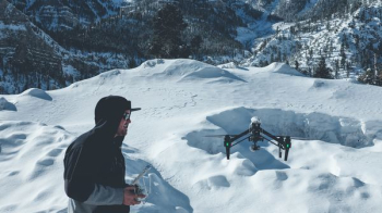 man in black hooded jacket controlling black drone man in black hooded jacket controlling black drone