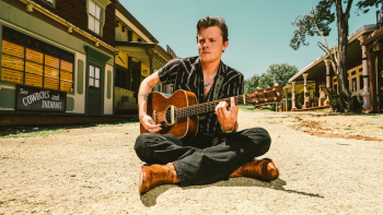 Man In Black Pants Sitting On Ground Playing Guitar Man In Black Pants Sitting On Ground Playing Guitar