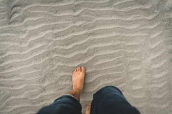 man in blue denim jeans walking through the sand man in blue denim jeans walking through the sand