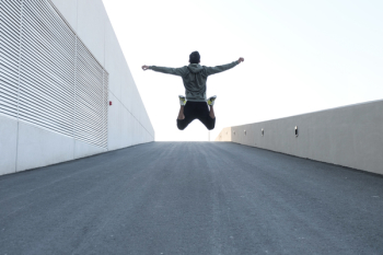 Man in Gray Hoodie Jump With Open Arms Man in Gray Hoodie Jump With Open Arms