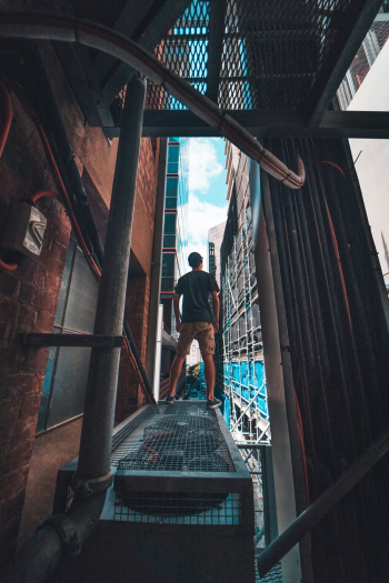 Man in Gray Shirt Standing on Gray Metal Scaffolding Man in Gray Shirt Standing on Gray Metal Scaffolding