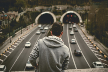 Man in Grey Hoodie Standing on Bridge over the Expressway Man in Grey Hoodie Standing on Bridge over the Expressway