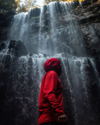 man in hooded jacket standing in front of waterfalls man in hooded jacket standing in front of waterfalls