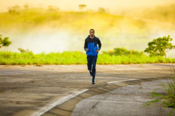 man in track suit jogging on concrete road man in track suit jogging on concrete road