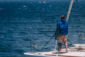 Man in White Hooded Jacket Riding on Boat Man in White Hooded Jacket Riding on Boat