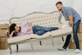 Man moving sofa with lying woman Man moving sofa with lying woman