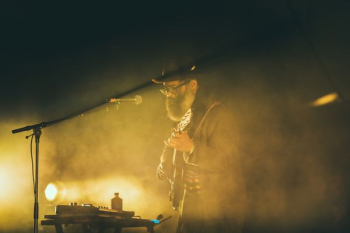 man playing guitar in front of black microphone man playing guitar in front of black microphone
