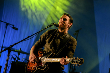 Man Playing Red and Black Electric Guitar on Stage Man Playing Red and Black Electric Guitar on Stage