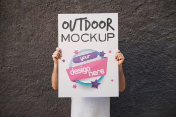 Man presenting poster mockup in front of wall Free Psd