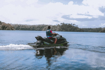 Man Riding on Green Personal Watercraft on Body of Water Man Riding on Green Personal Watercraft on Body of Water