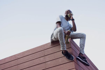 man sit on roof top while holding phone and bottle man sit on roof top while holding phone and bottle