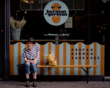 Man Sits Outside Herman ze German Store Man Sits Outside Herman ze German Store
