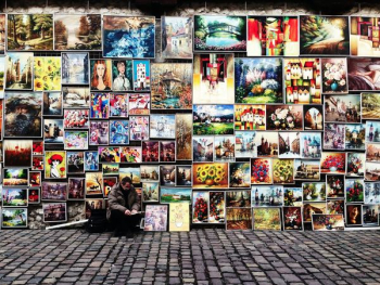 man sitting beside painting lot man sitting beside painting lot