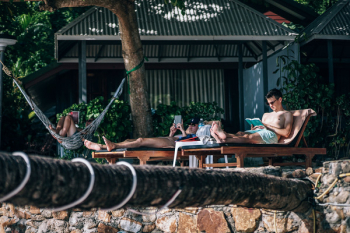 Man Sitting on Brown Wooden Lounger Man Sitting on Brown Wooden Lounger