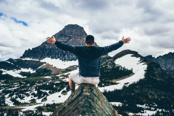 man sitting on cone rock spreading hands man sitting on cone rock spreading hands