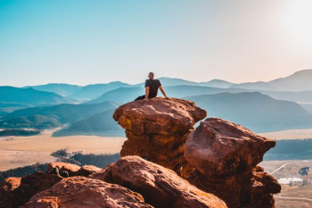 man sitting on rock formation man sitting on rock formation