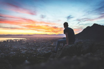 man sitting on rock in front of sea man sitting on rock in front of sea