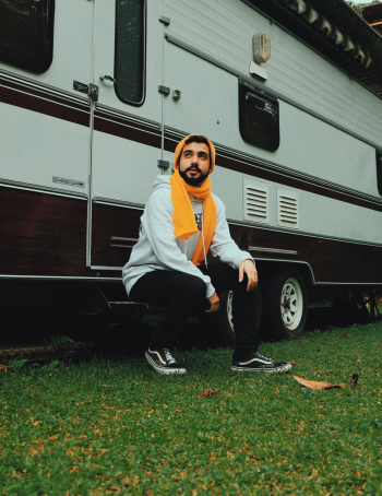 Man Sitting on White and Brown Recreational Vehicle Man Sitting on White and Brown Recreational Vehicle