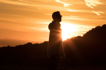 man standing at the peak of mountain under golden hour