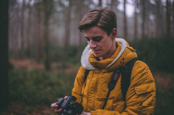 man standing holding DSLR on forest