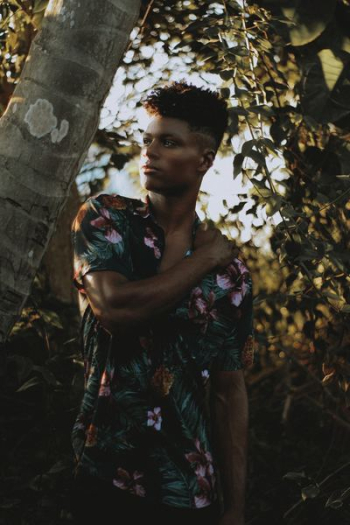 man standing holding shoulder near the coconut tree