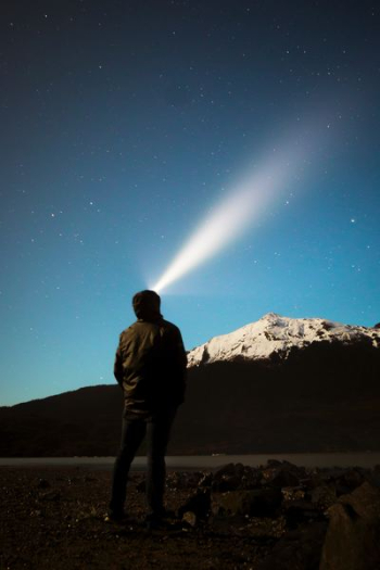 man standing in front of mountain watching light on sky man standing in front of mountain watching light on sky