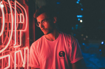 man standing in front of pink neon light signage man standing in front of pink neon light signage