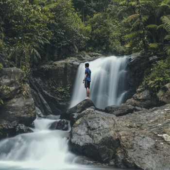 man standing on rocks with waterfalls background man standing on rocks with waterfalls background