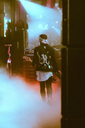 man standing on stage while holding guitar man standing on stage while holding guitar