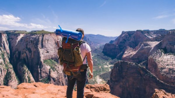man standing on top of mountain facing mountain view man standing on top of mountain facing mountain view