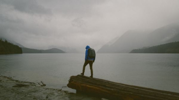 man standing on wooden platform in front of water during daytime man standing on wooden platform in front of water during daytime