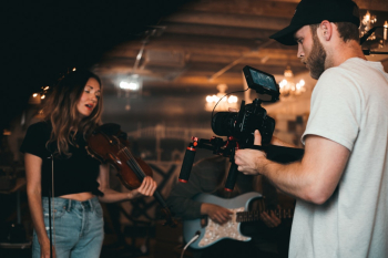 Man Taking a Video of a Woman Carrying a Violin Man Taking a Video of a Woman Carrying a Violin
