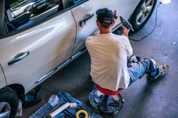 man using glue gun on silver car man using glue gun on silver car