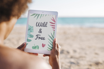 Man using tablet mockup at the beach Free Psd