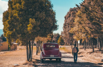 man walking beside red car man walking beside red car