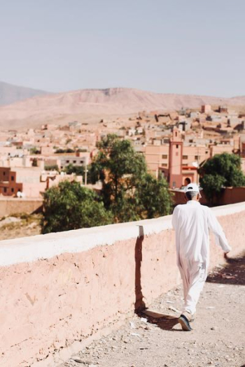 man walking beside white concrete wall