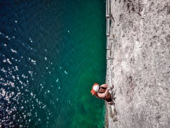 Man Wall Climbing Near Body of Water Man Wall Climbing Near Body of Water