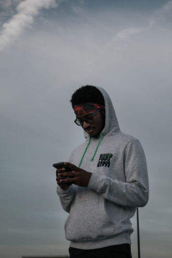 Man Wearing a Hoodie Holding Smartphone Man Wearing a Hoodie Holding Smartphone