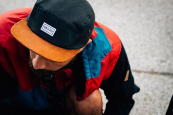 man wearing black and orange Baxin cap looking down man wearing black and orange Baxin cap looking down