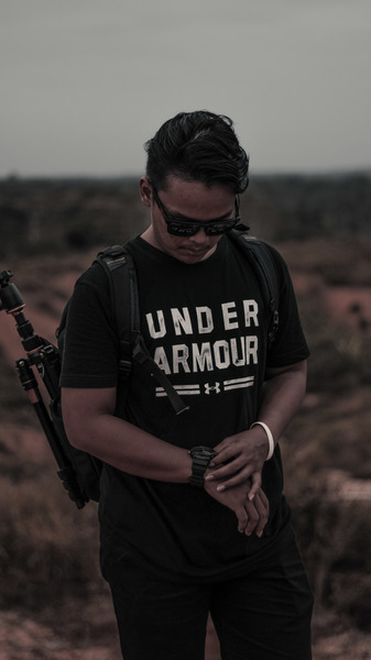 Man Wearing Black and White Under Armour Shirt and Holding His Watch