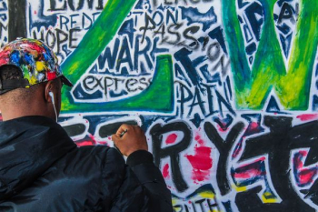 man wearing black jacket painting graffiti man wearing black jacket painting graffiti