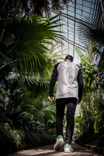 Man Wearing Black Jeans Walking Besides Green Plants Man Wearing Black Jeans Walking Besides Green Plants