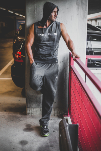 Man Wearing Black Tracksuit Standing Beside Red Metal Fence
